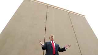 Trump se dirige a la prensa delante de un prototipo del muro de México.