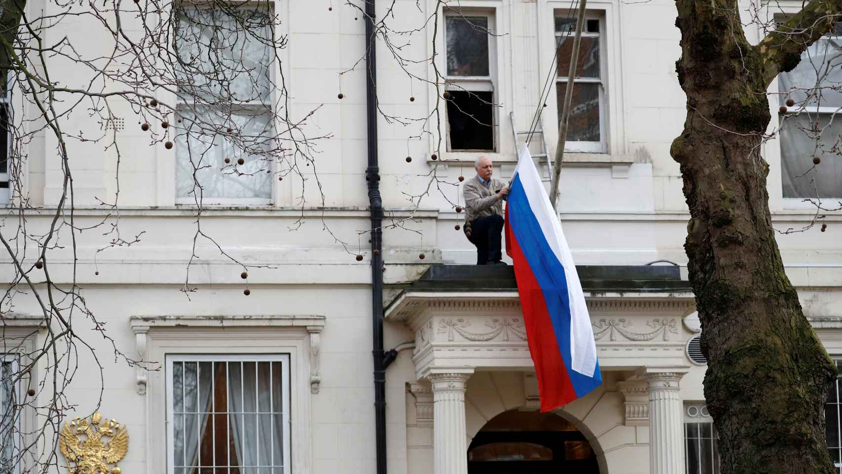 Un hombre retira la bandera rusa de la Embajada de Rusia en Londres.