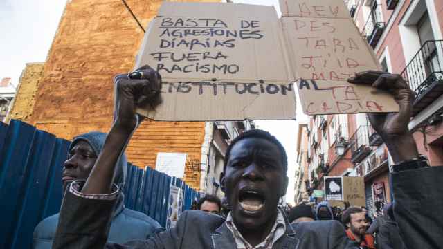 Un manifestante en Lavapiés muestra un cartel de protesta contra el racismo institucional.