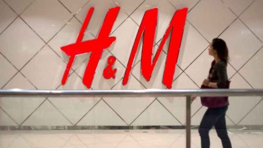 Una mujer pasea ante el logo de H&M.