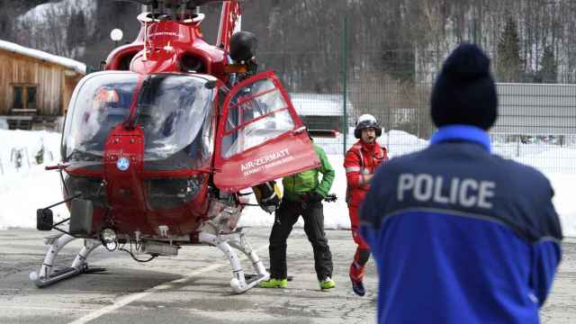 Un policía observa el aterrizaje del helicóptero de Air Zermatt tras la búsqueda en la zona donde se produjo el alud, en Valais.