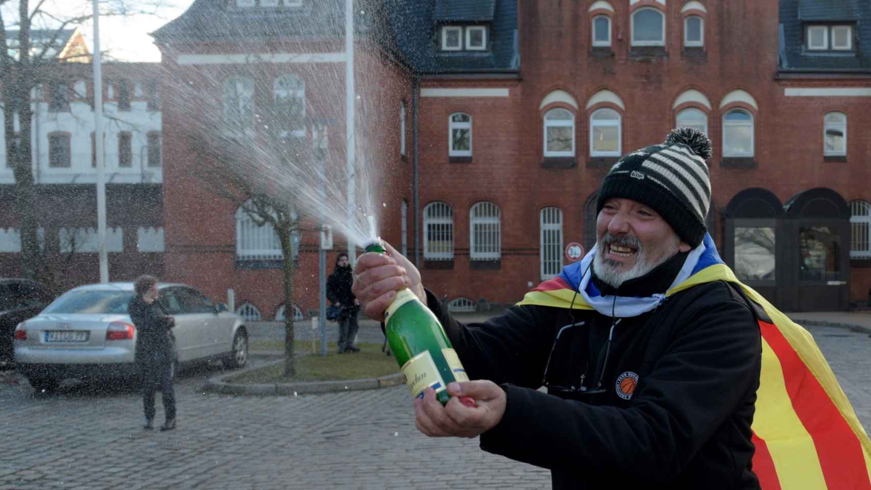 Un hombre con una bandera estelada celebra con champán frente la cárcel de Neumünster.