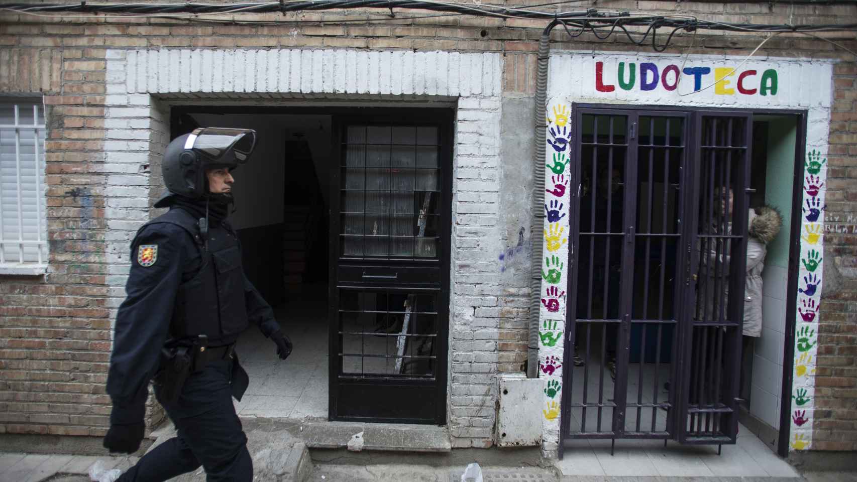 Un agente de la UIP pasa por delante de una ludoteca del barrio de Almanjáyar.