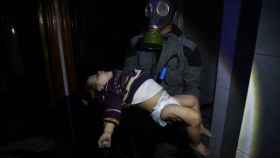 Un miembro de un equipo de rescate sujeta el cadáver de un niño tras el ataque químico en Duma.