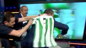 Roncero intenta poner la camiseta del Betis a Cristóbal Soria. Foto: Twitter (@elchiringuitotv)