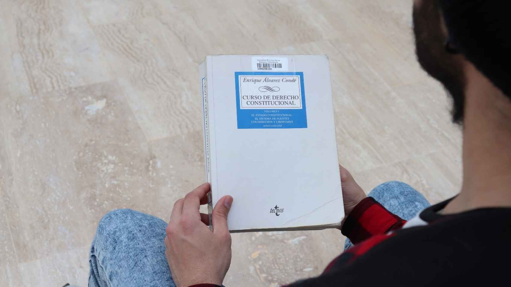 El manual de Álvarez Conde en manos de un alumno de la URJC.