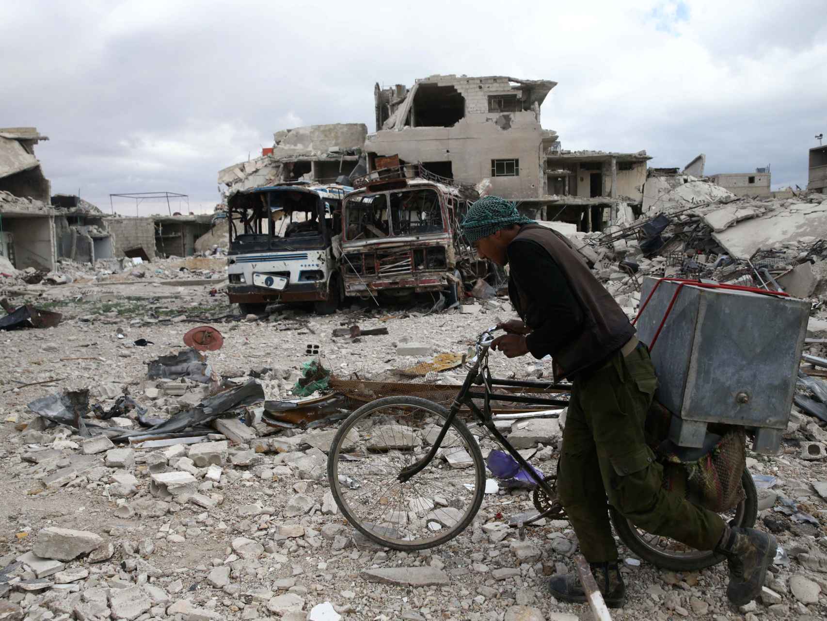 Un hombre camina con su bicicleta entre los escombros de Duma, en Siria.