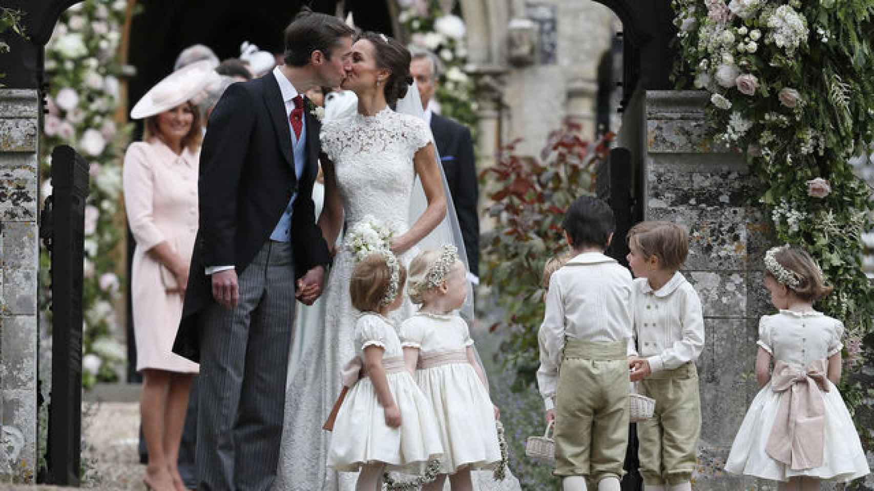 Los novios besándose a la salida de la iglesia ante la atenta mirada de los pequeños en el día de su boda. GTRES.