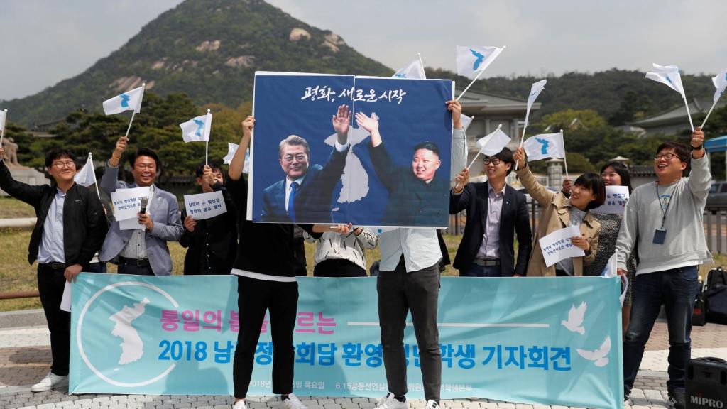 Un grupo de estudiantes sostiene dos carteles de Kim Jong-un y Moon Jae-in.