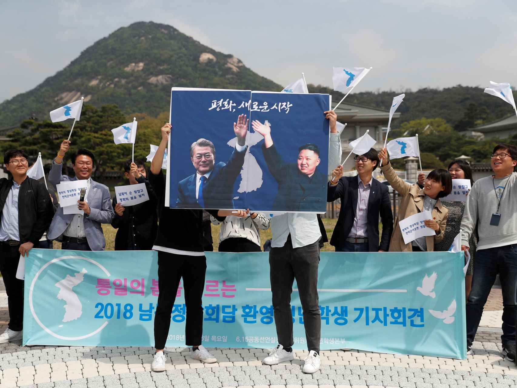 Un grupo de estudiantes sostiene dos carteles de Kim Jong-un y Moon Jae-in.