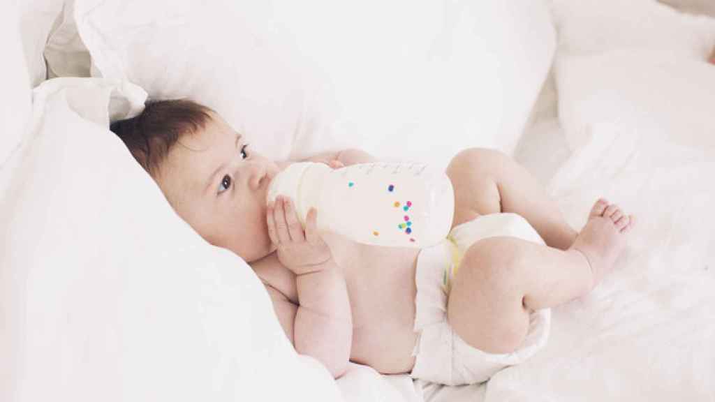 Un bebé disfruta de leche en un biberón.