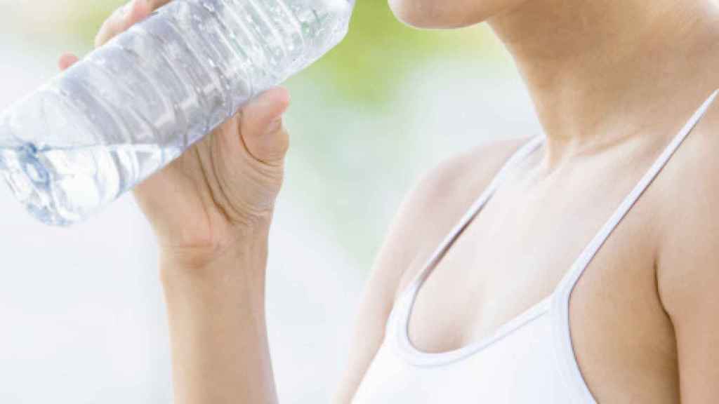 Una joven bebiendo de una botella de plástico.