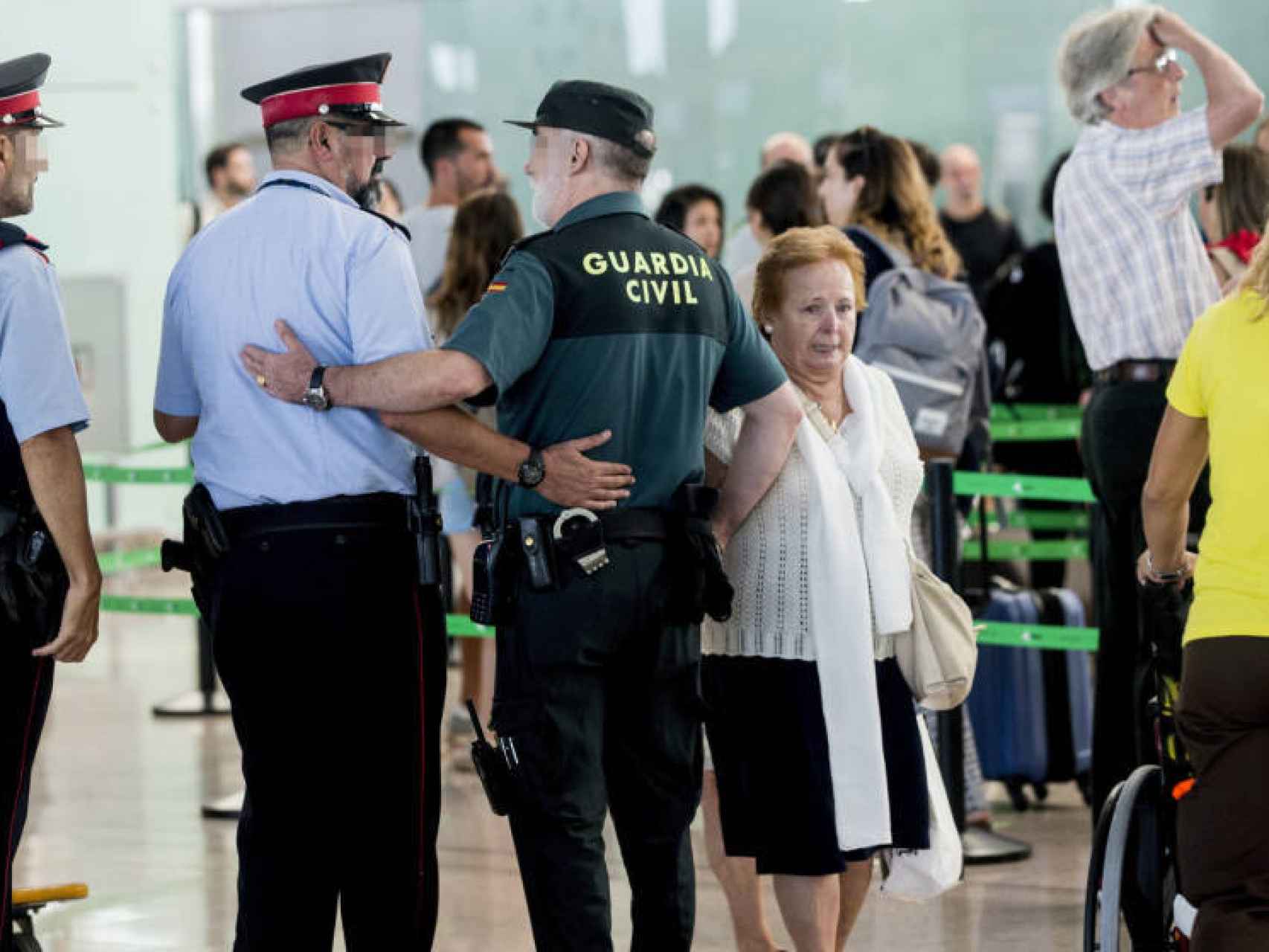 Un agente de la Guardia Civil en el aeropuerto de Barcelona, junto a dos mossos.