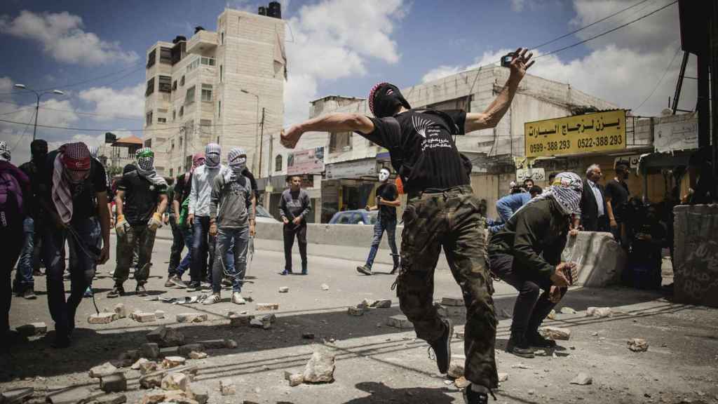 Un grupo de manifestantes palestinos lanza piedras durante los enfrentamientos.