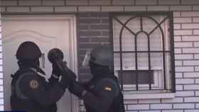 Agentes derribando la puerta de una de las viviendas registradas en la operación.