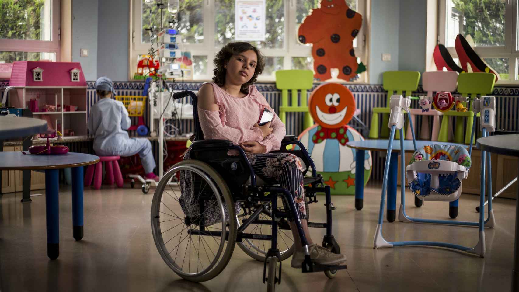 Paula López, de doce años, rodeada de juguetes para niños pequeños, en el área de oncología pediátrica del Hospital Virgen del Rocío.