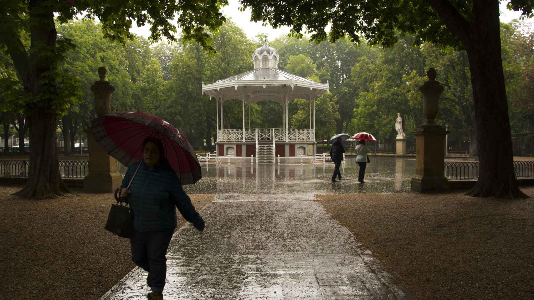 Paseantes se protegen de la lluvia en el parque de la Florida de Vitoria. (Archivo)