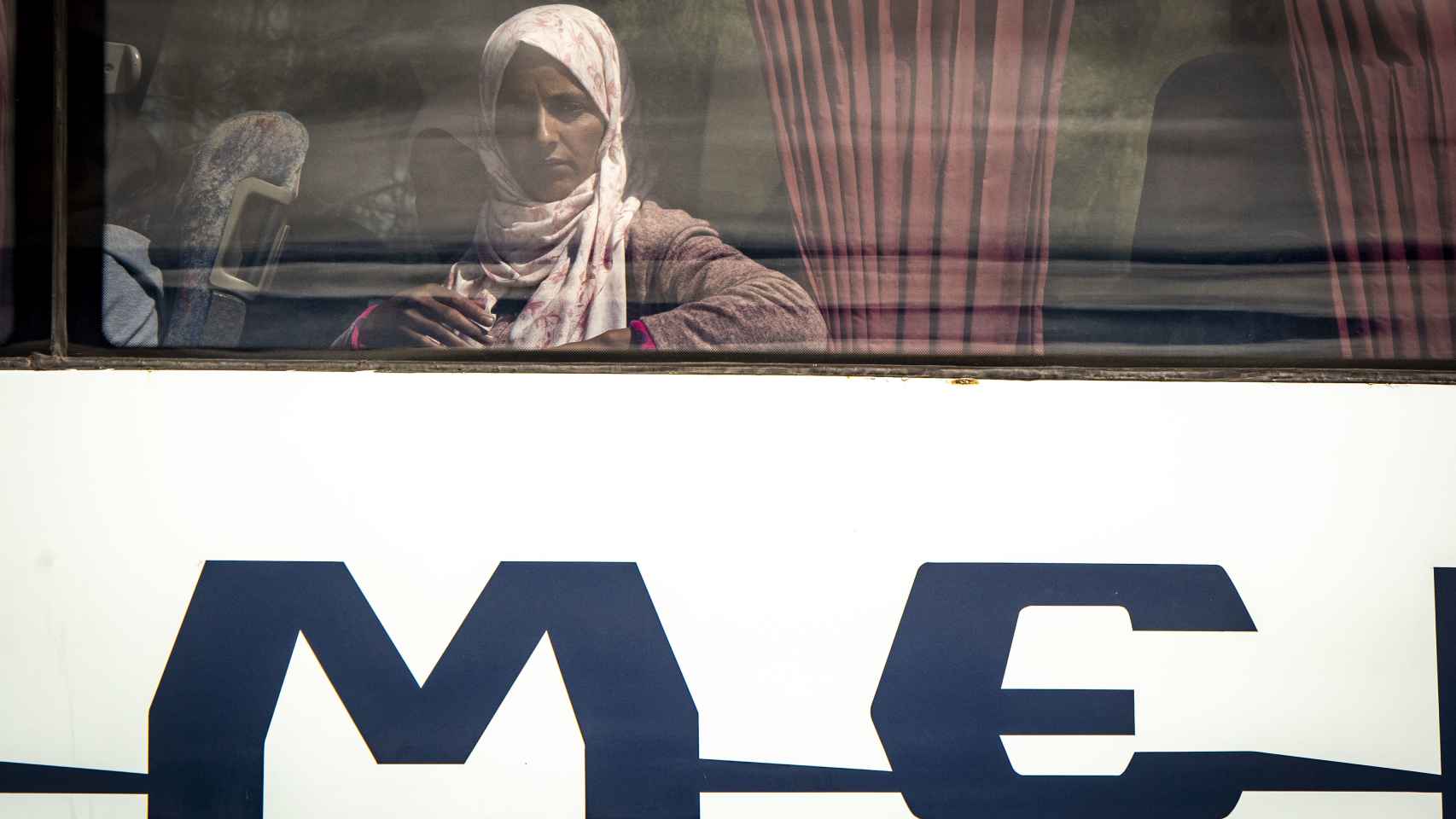 Una jornalera mira por la ventana de uno de los autobuses que esta semana han comenzado a trasladar mujeres marroquíes a su país tras trabajar en la campaña de recogida de la fresa en Huelva.