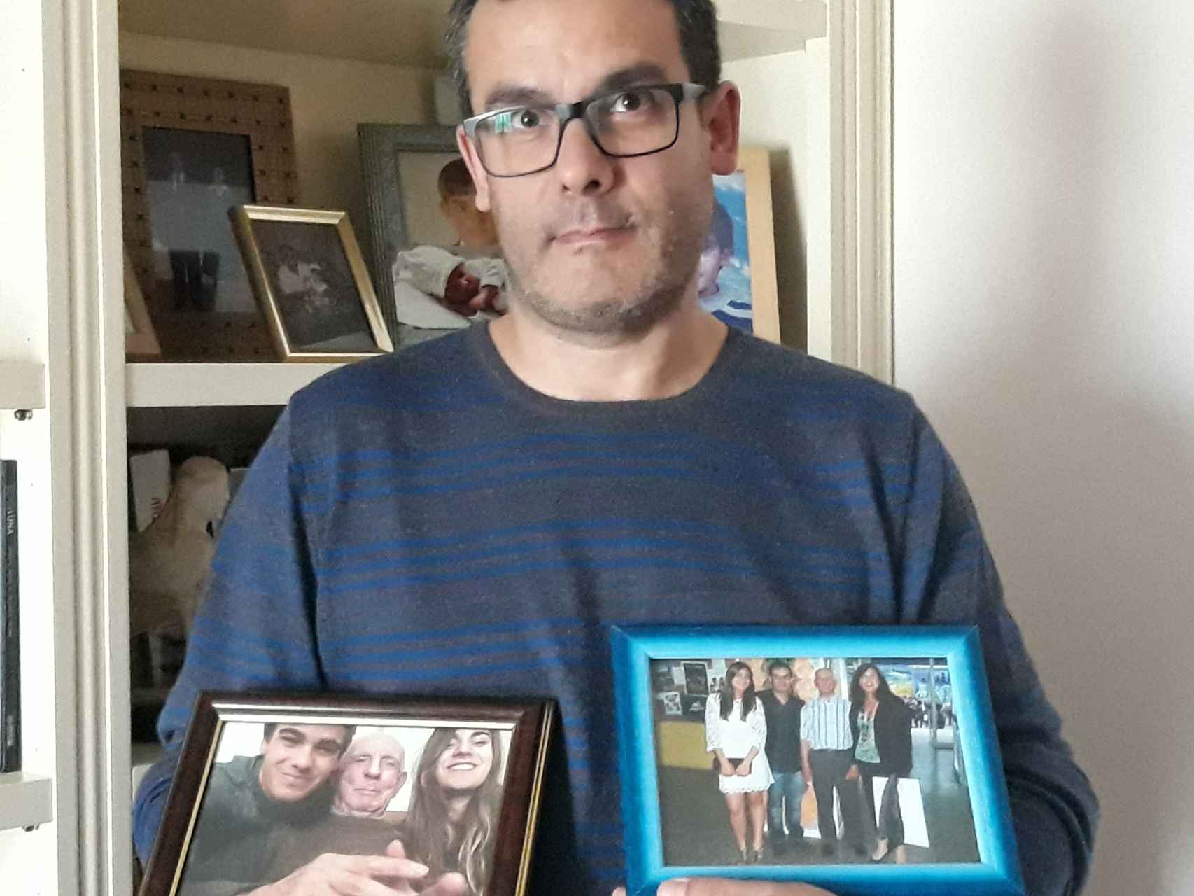 Juan Carlos sosteniendo dos fotos de su padre con sus hijos.
