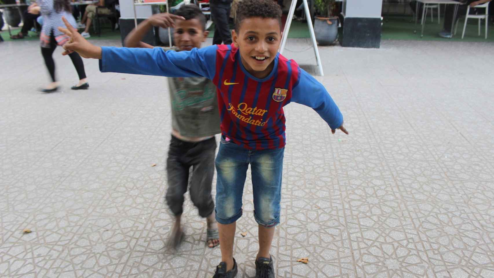 Un niño, aficionado del Barça, saluda durante el partido