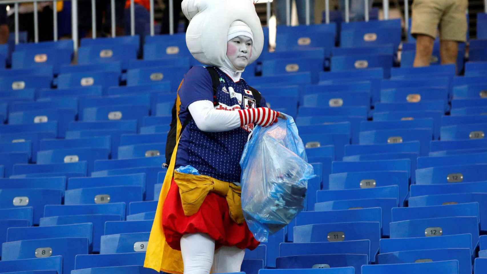 Aficionados de Japón recogen los desperdicios de las gradas tras el partido ante Bélgica.