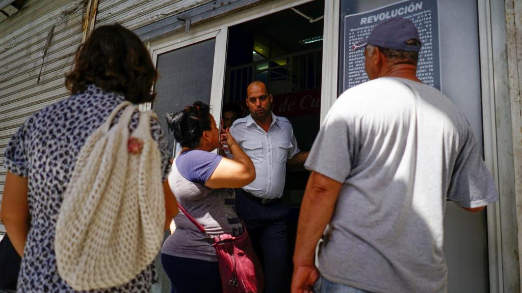 Algunos clientes pidiendo información a un empleado de Cubana.