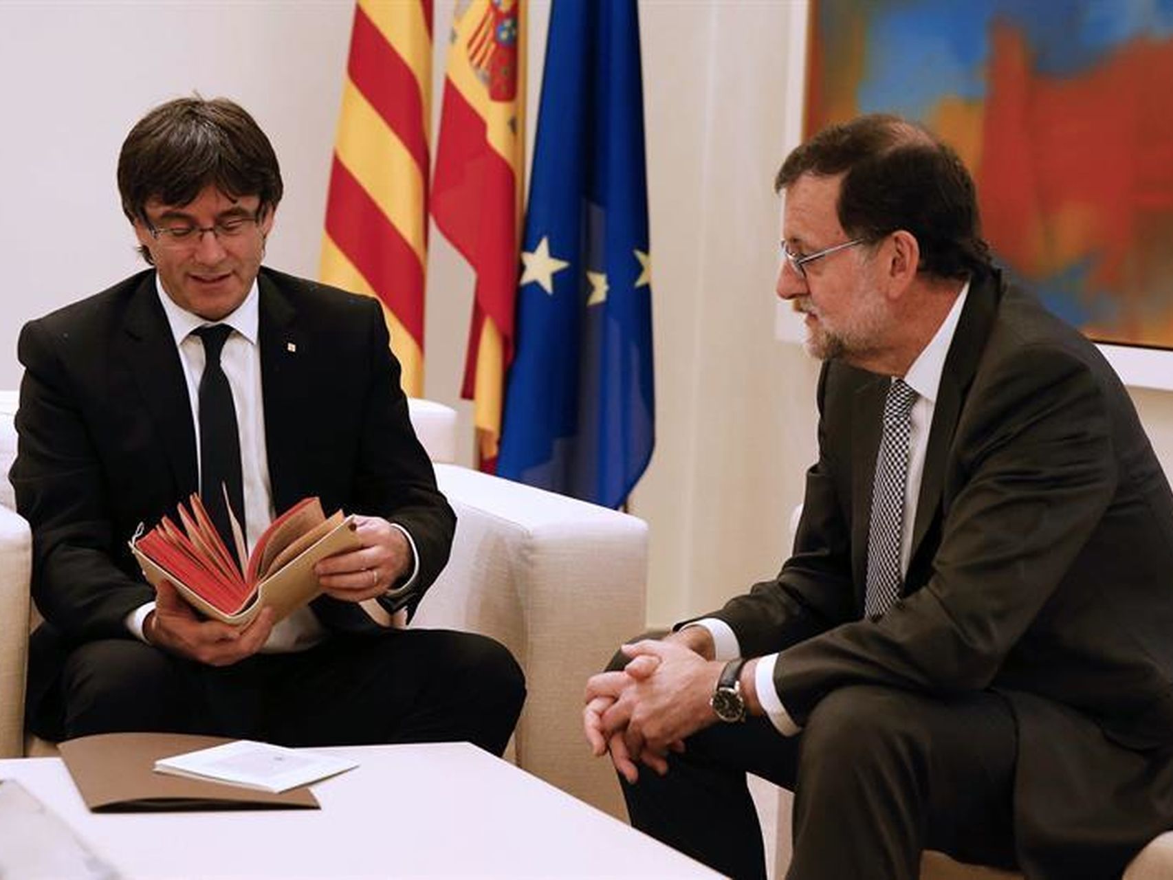 Puigdemont hojeando el regalo de Rajoy, hace dos años.
