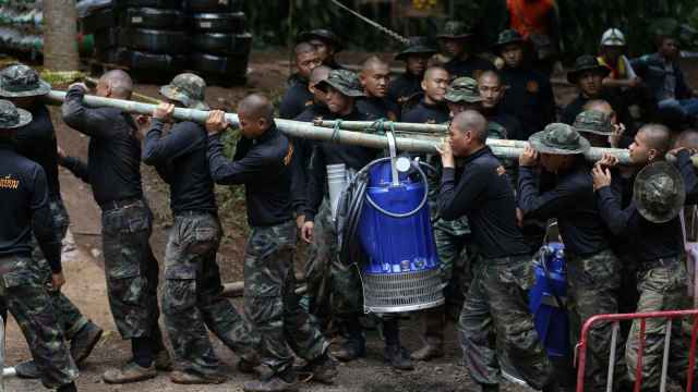 Militares tailandeses transportan una bombona de oxígeno hacia la cueva.