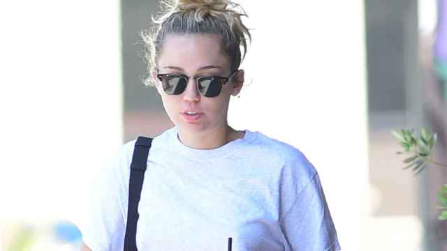 Miley Cyrus con gafas de sol y un moño despeinado.