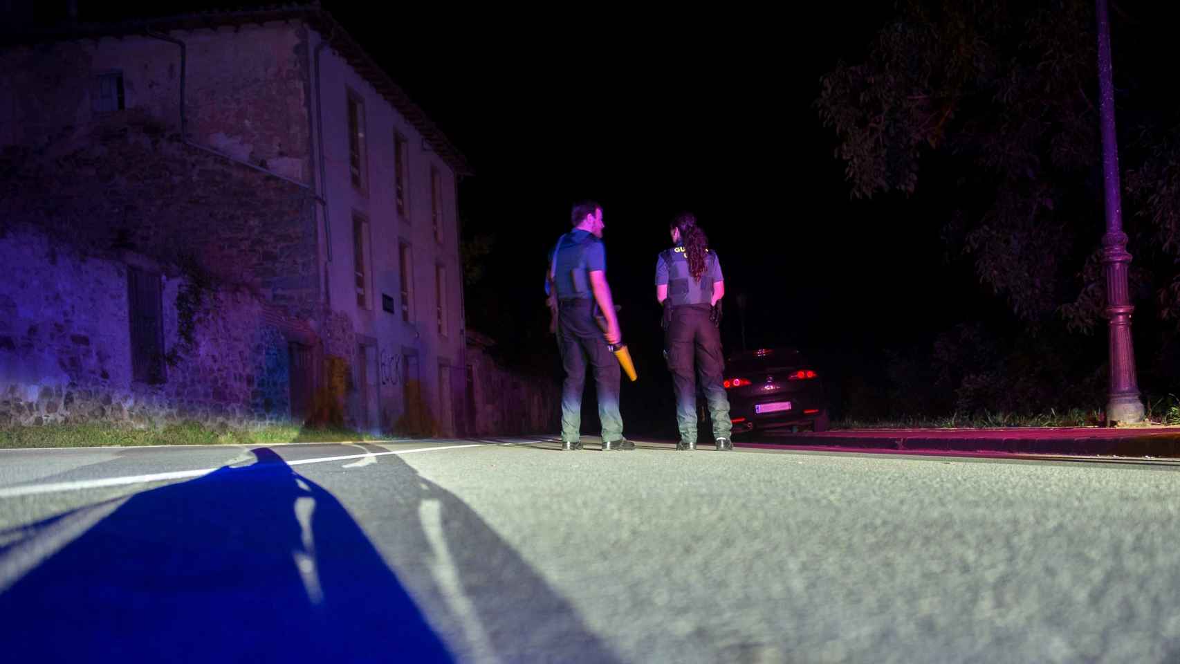 Dos agentes de la Guardia Civil cortan la carretera que da acceso al lugar en el que un hombre se ha atrincherado esta madrugada.