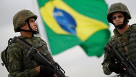 Militares delante de una bandera de Brasil.