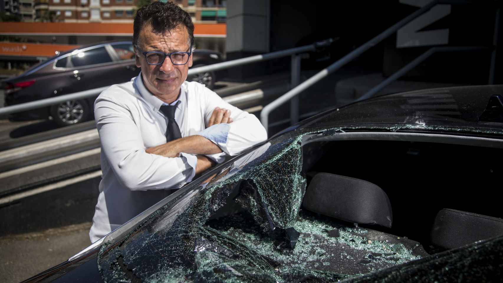 Rafael Navarro, chófer de Cabify en Barcelona, posando ante uno de los vehículos siniestrados.