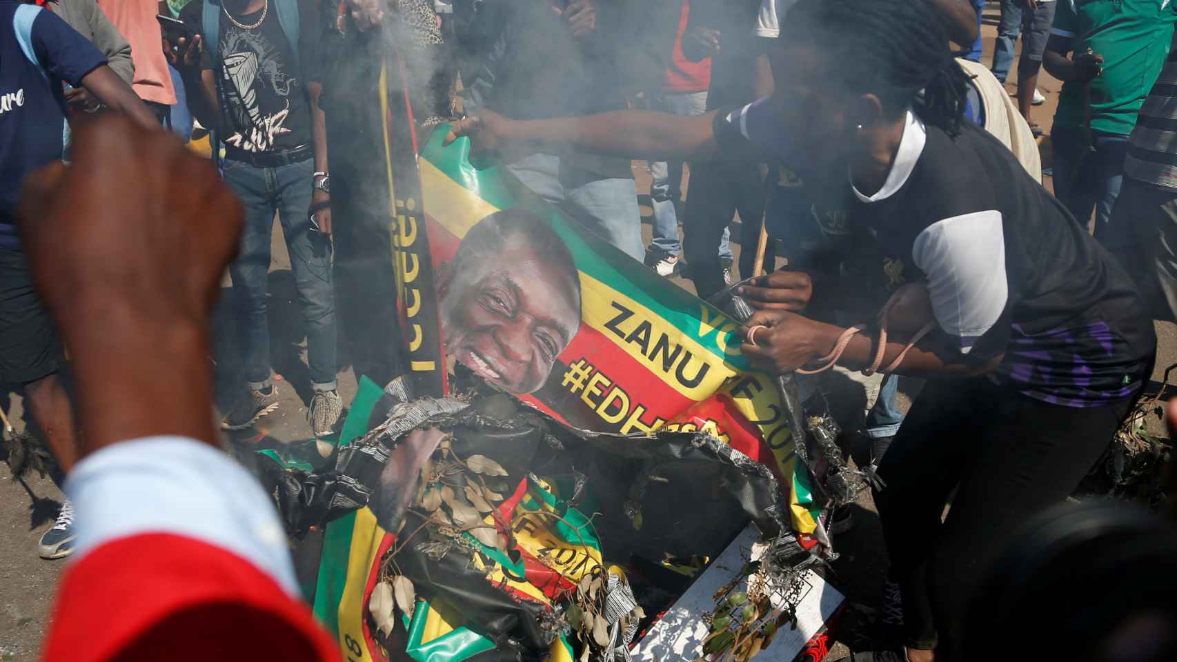 Los partidarios del partido Movimiento por el Cambio Democrático (MDC) queman una pancarta electoral con la cara del presidente de Zimbabwe, Emmerson Mnangagwa.