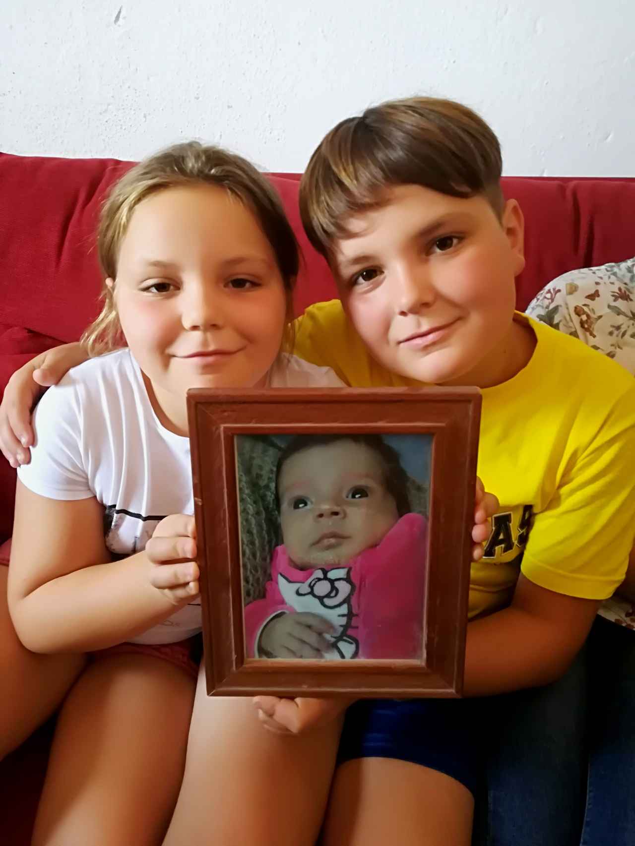 Paqui, de nueve años, y Tomás, de 11, sostienen un retrato de su hermana Marta recién nacida. Hoy la niña tiene ya seis años.