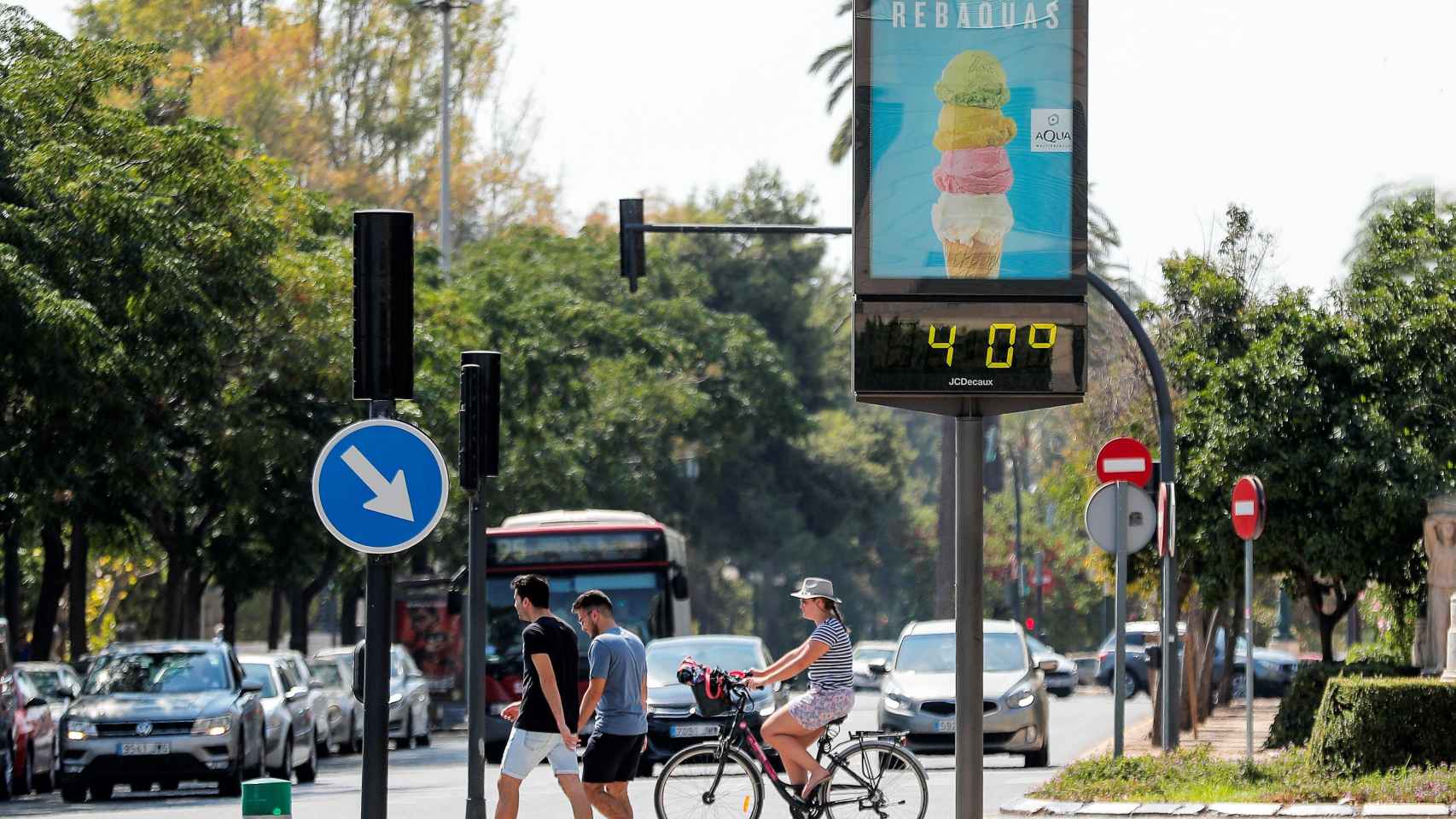 Varias personas pasan, este mediodía en la ciudad de Valencia, ante un termómetro urbano que marca una temperatura de 40º acompañados por la sensación de bochorno