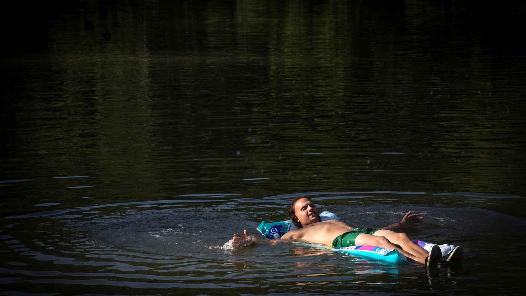Un hombre se refresca en el río Arga a su paso por Pamplona.