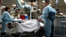 Un paciente rodeado de dos médicos en el quirófano de un hospital.