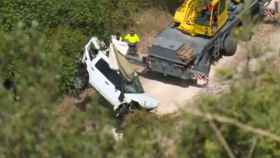 Una grua sube los restos del Land Rover destrozado