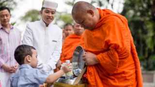 Un monje recibiendo una ofrenda.