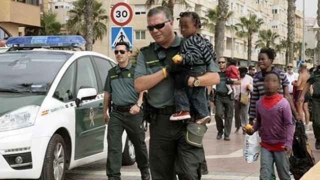 Agentes de la Guardia Civil en Melilla trasladan a un grupo de inmigrantes llegados a España, incluidos menores.