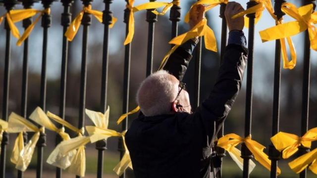 Un hombre retira lazos amarillos en Barcelona.