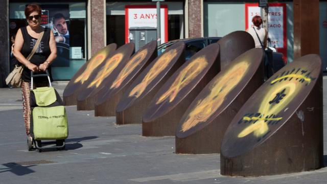 Una mujer pasa ante unos lazos amarillos en el barrio de Sants de Barcelona.