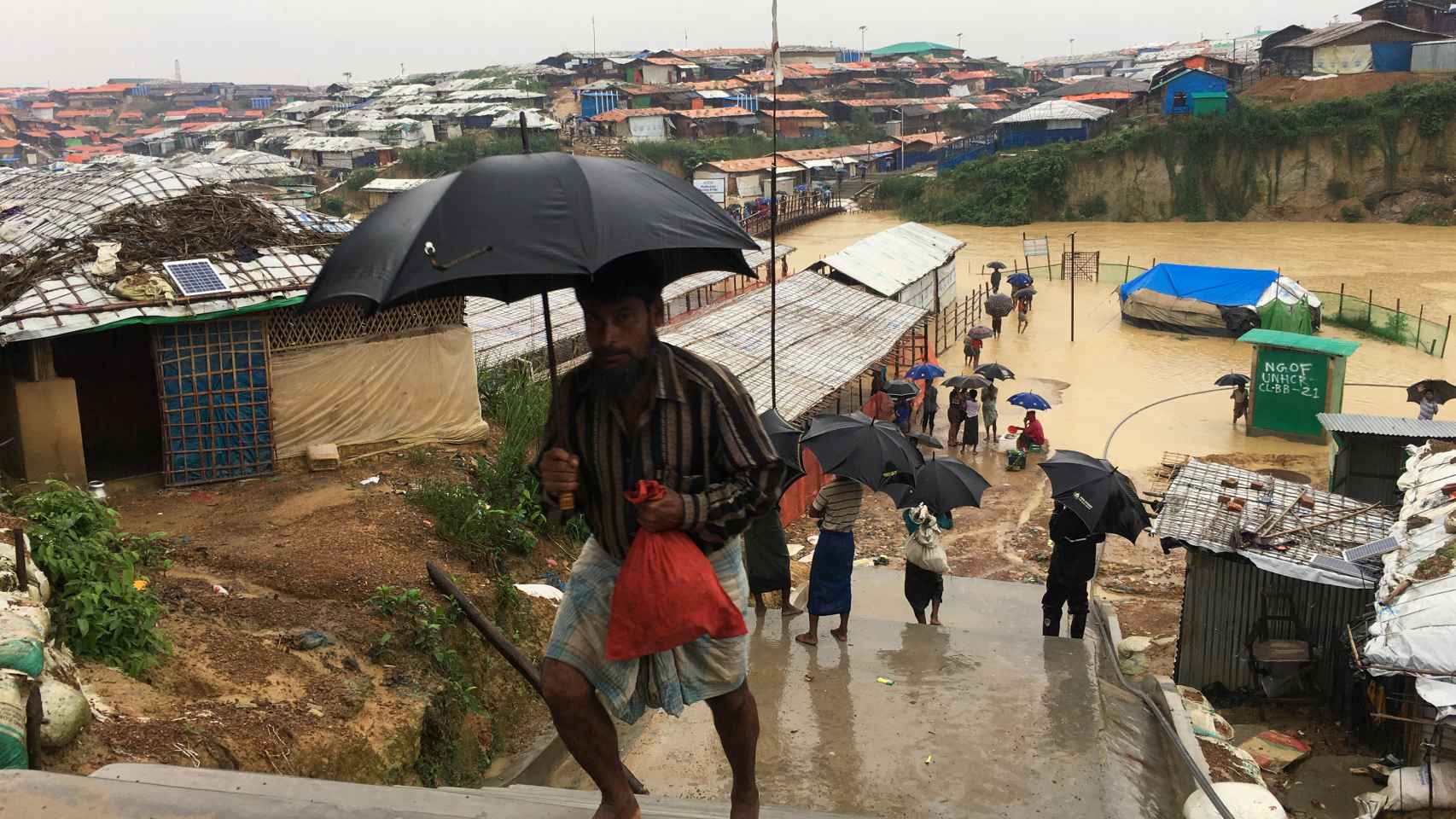 Algunos rohingyas caminan en el campo de refugiados bajo la lluvia en Cox's Bazar.