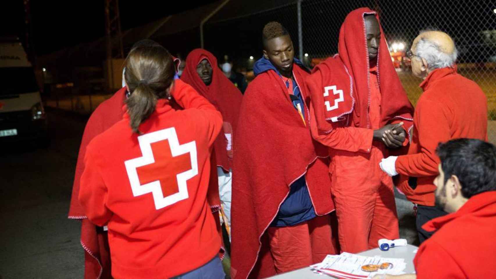Miembros de la Cruz Roja atienden a inmigrantes recién desembarcados en el puerto de Motril.