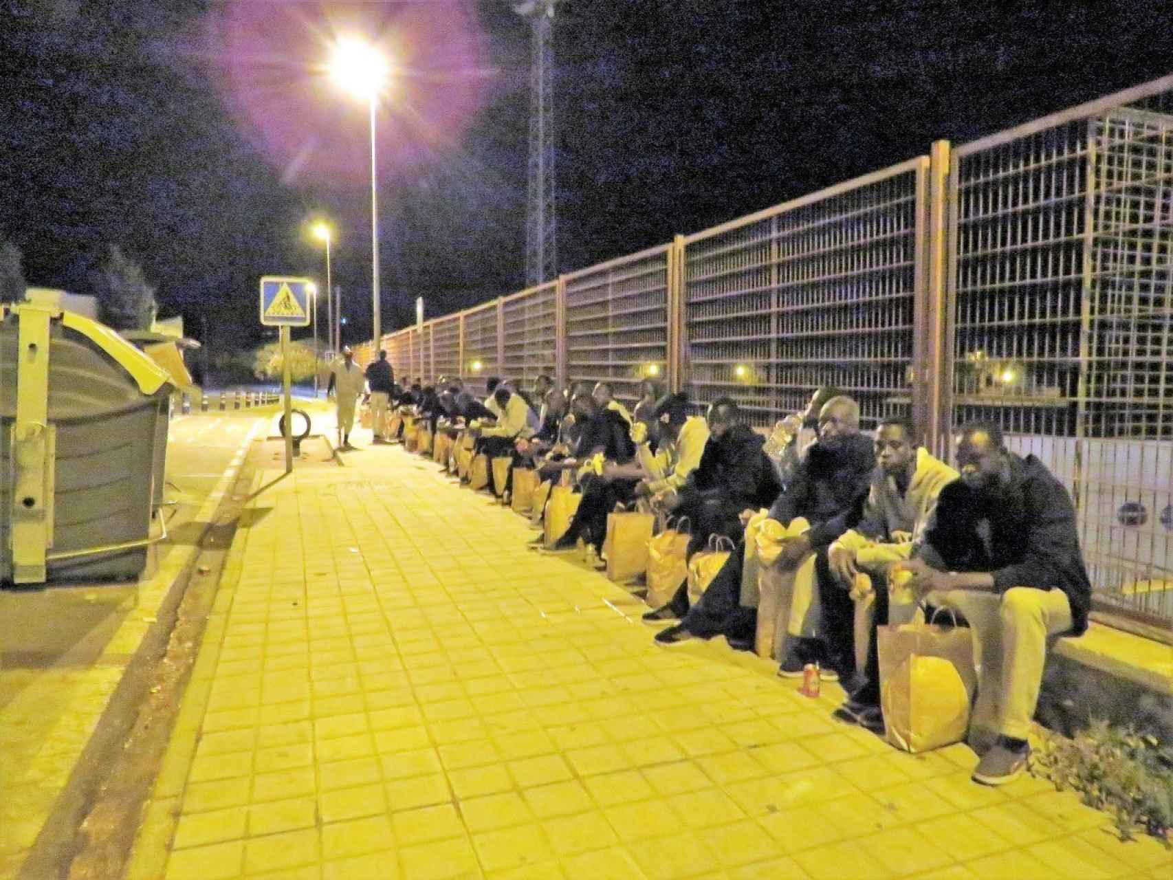 Los migrantes esperando al 'bus de la vergüenza' esperando.