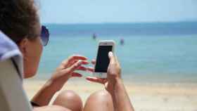 Una mujer mira el móvil mientras está en la playa.