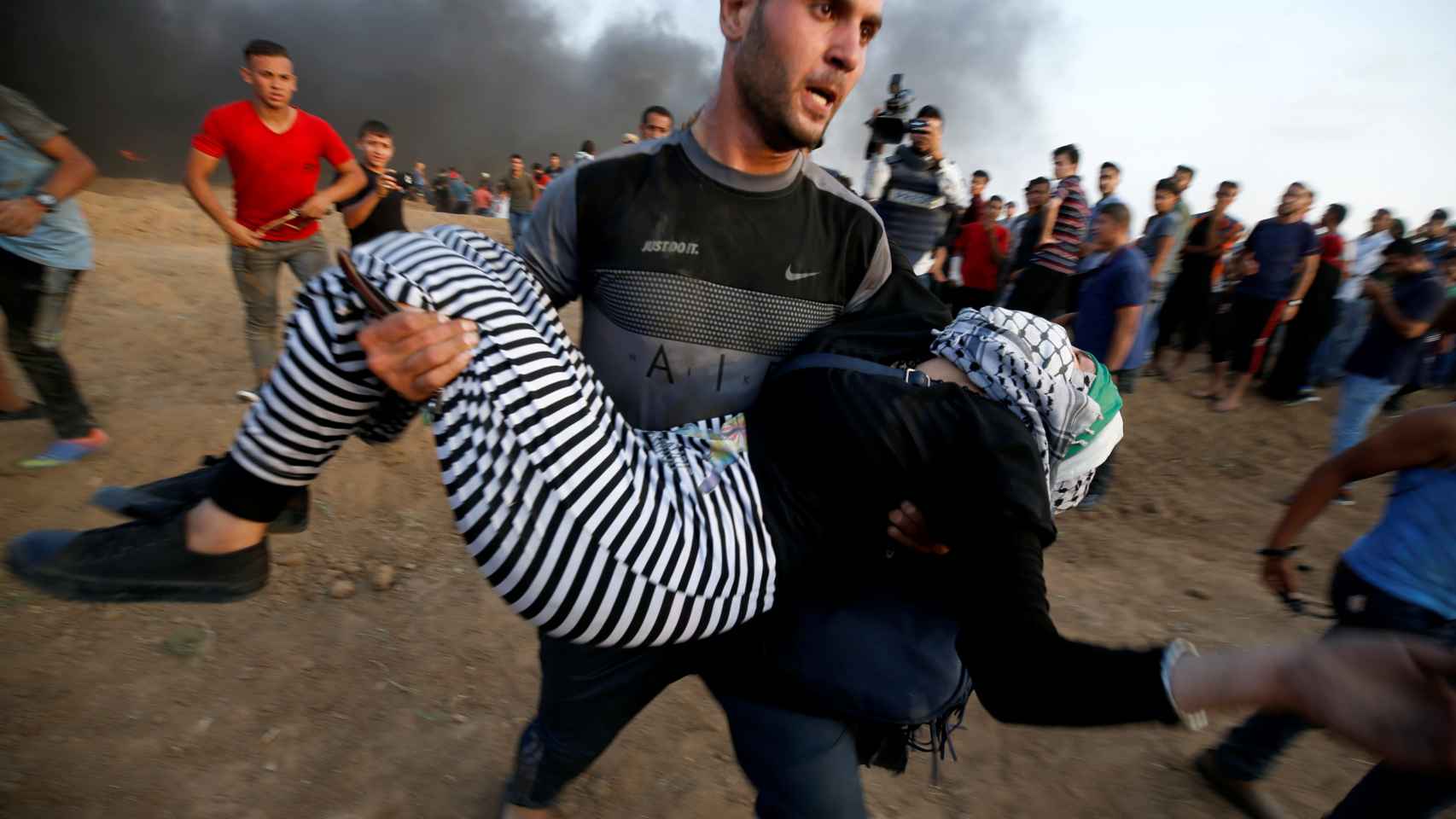 Un palestino sostiene a una mujer herida durante una protesta en la frontera entre Israel y Gaza.