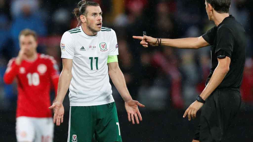 Bale discute con el árbitro durante un partido de Gales
