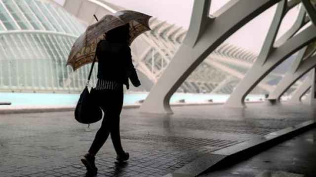 Una persona se resguarda de la lluvia en la Ciudad de las Ciencias de Valencia.