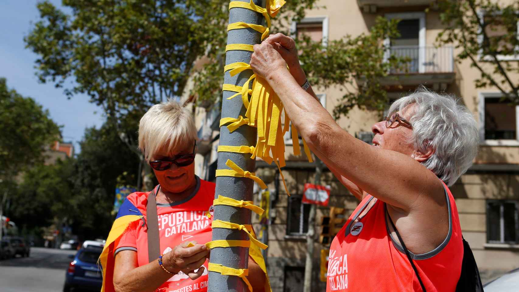 Dos mujeres atando lazos amarillos en Barcelona.